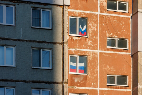 typical russian ugly high rise apartmant building with russian national flags in some windows at summer day.