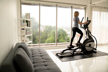 Fit woman using stationary bike for cardio workout at home. Healthy and sporty lifestyle concept