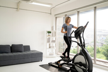 Fit woman using stationary bike for cardio workout at home. Healthy and sporty lifestyle concept