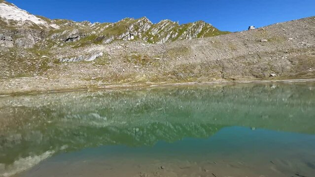 View of alpine lake with clear water at the feet of the Giogo Lungo refuge, Valle Aurina, Italy