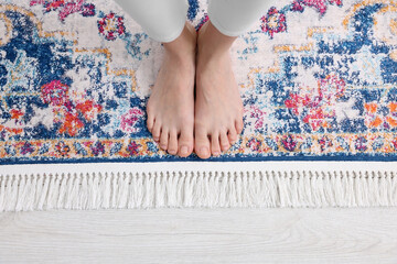 Woman standing on carpet with pattern at home, top view