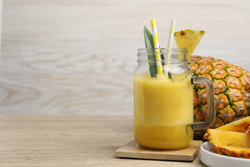 Tasty pineapple smoothie and fruit on wooden table. Space for text