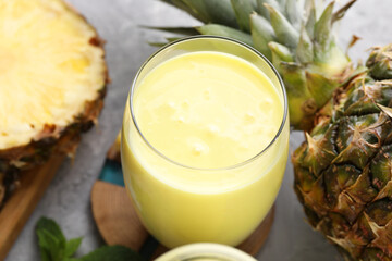 Tasty pineapple smoothie, mint and fruit on grey textured table, closeup