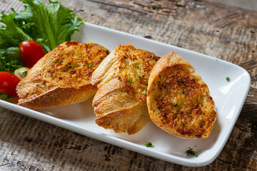 Fresh crispy garlic bread on white plate