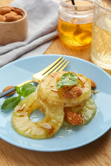 Tasty grilled pineapple slices served with mint and almonds on table