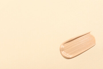 Smear of skin foundation on beige background, top view. Space for text