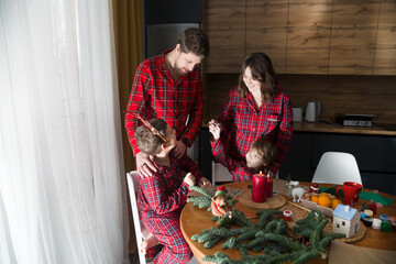 family mom, dad and two children brothers in red pajamas write a letter to Santa and do Christmas...