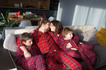 family mom, dad and two children brothers in red pajamas on Christmas morning at home.