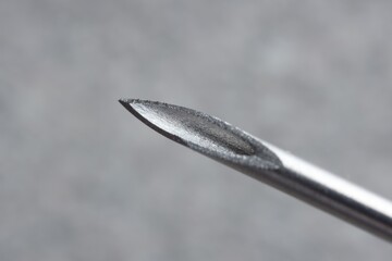 Macro photo of medical needle on blurred grey background