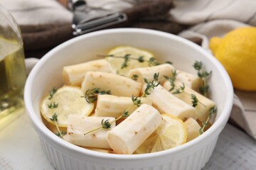 Dish with raw salsify roots, lemon and thyme on table, closeup