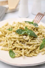 Plate of delicious trofie pasta with pesto sauce, cheese and basil leaves on table, closeup