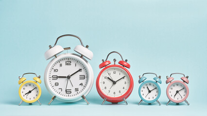 Five alarm clocks of different colors show different times. Start of the day, waking up, morning,...