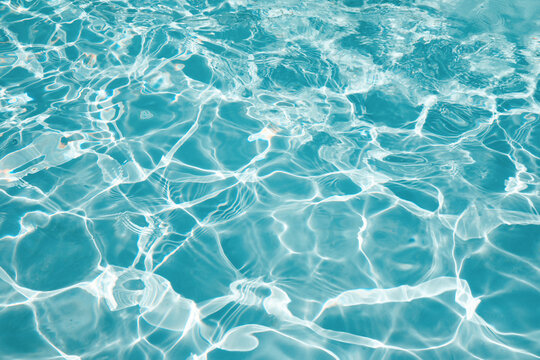 Abstract water background with ripples. Light caustics effect. Play of light and shadow, texture of twaves and splashes.