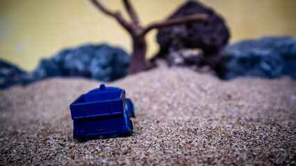 South Minahasa, Indonesia - February 2, 2023: Toy car in the sand on a yellow background looks like afternoon
