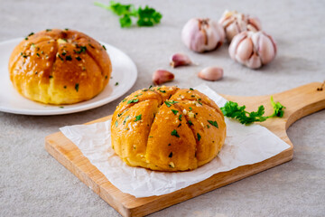 Korean cream cheese garlic bread on wooden board and raw garlic cloves.
