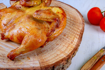 Tender juicy whole grilled BBQ roasted chicken was beautifully displayed on a wooden board.
