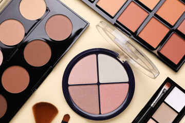 Colorful contouring palettes with brushes on beige background, flat lay. Professional cosmetic...