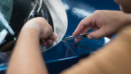 The master in the car service cuts the protective cutter. 