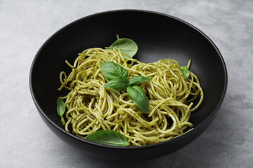 Delicious pasta with pesto sauce and basil on light grey table, closeup
