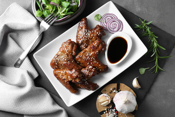 Chicken wings glazed with soy sauce served on grey table, flat lay