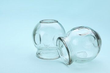 Glass cups on light blue background, closeup with space for text. Cupping therapy