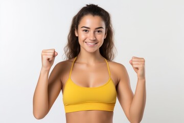 Obraz na płótnie Canvas Portrait of a smiling sportswoman in yellow sportswear showing her biceps isolated on a white background and Looking at the camera.