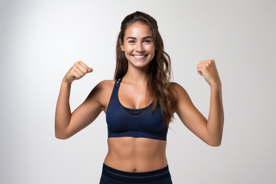 Portrait of a smiling sportswoman in deep blue color sportswear showing her biceps isolated on a white background and Looking at the camera.