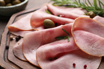 Slices of delicious ham with rosemary and spices on wooden board, closeup