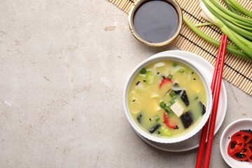 Bowl of delicious miso soup with tofu served on light grey table, flat lay. Space for text