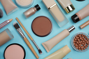 Face powders and other decorative cosmetic products on light blue background, flat lay