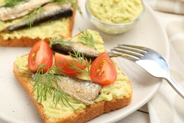 Fototapeta na wymiar Delicious sandwiches with sprats, tomatoes, dill and avocado puree served on white table, closeup