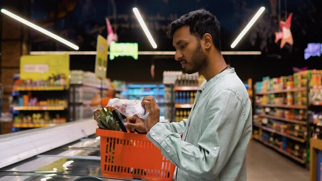 Indian man shopping for frozen fish seafood in supermarket retail store