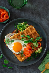 waffle with fried egg, smoked salmon, avocado and cucumber for breakfast