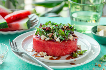 watermelon steak with feta cheese, greens and nuts, fresh raw summer meal