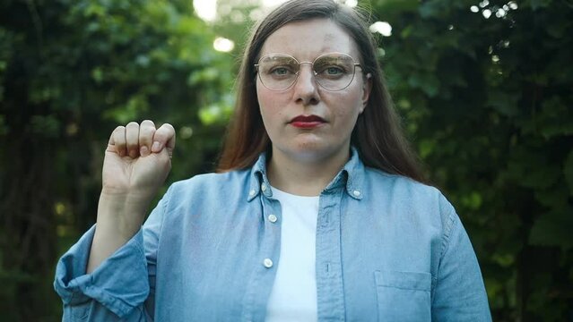 Signal for help. Woman shows how to make hand gesture to ask for help silently outdoors. High quality FullHD footage