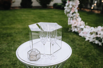 Wedding accessories, details: glass box, money box, wine glasses stand on the table, rack outdoors...