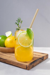 Fototapeta premium Drink with orange lemon and lime in glass transparent glasses on a concrete background. Lemonade with ice. Front view