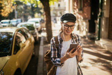 Young Asian student using a smartphone while walking in the city