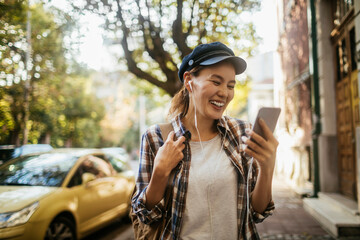 Happy young Asian woman using a smartphone while walking in the city