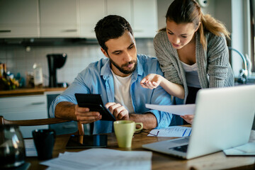 Worried young Caucasian couple going over their bills and home finances in the morning in the kitchen