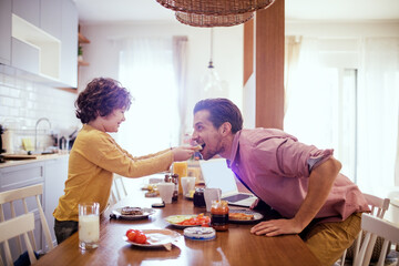 Happy young single father having breakfast with his son in the morning in the kitchen