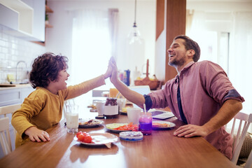 Obraz premium Single father having breakfast with his son in the morning in the kitchen