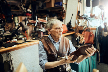 Senior male cobbler restoring a shoe in his old workshop in the city
