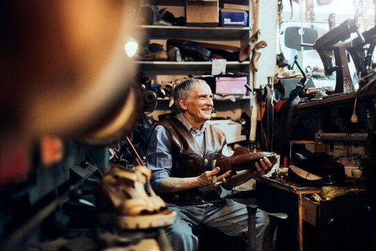 Senior male cobbler restoring a shoe in his old workshop in the city