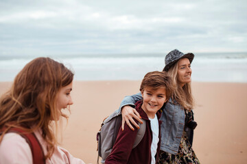 Fototapeta na wymiar Single mother taking her kids for a walk on a sandy beach in Lisbon