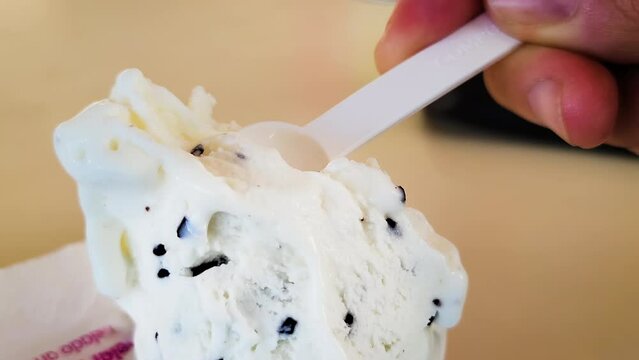 Closeup shot of a hand taking a spoonful of the soft stracciatella italina ice cream