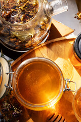 beautiful fresh natural golden  linden honey in big glass jar  at wooden tray with sunny light inside. close up