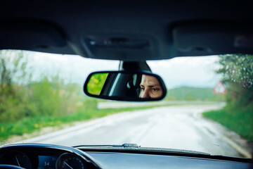 Attentive eyes of a female driver in the rearview mirror while driving, traveling by car