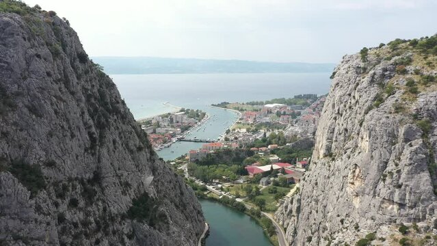 Old towns of Croatia. Summer holidays. Yachting. Cetina River winding its way through Rugged mountains gorge into adriatic sea in Omis Town. Aerial. Morning