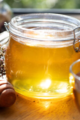 beautiful fresh natural golden  linden honey in big glass jar  at wooden tray in beautiful sunny light. close up